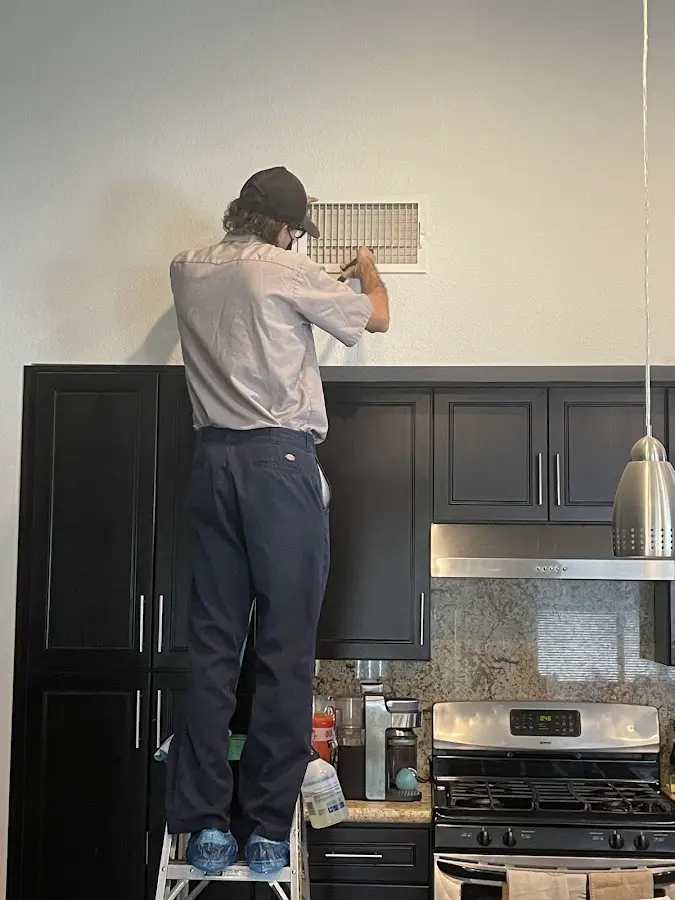 Technician inspecting an air vent during HVAC service in Old Jamestown